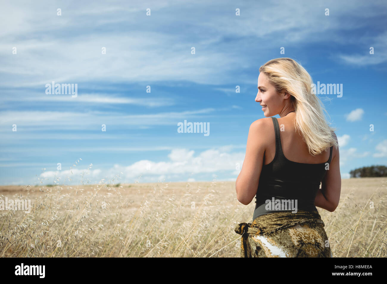 Rear view of blonde woman standing in field Stock Photo