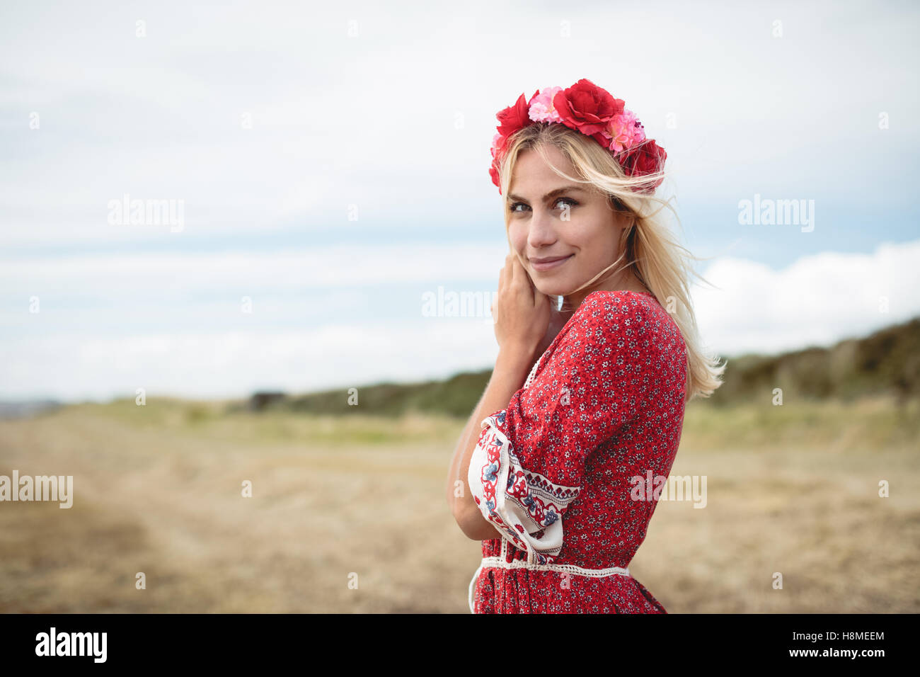 Blonde woman wearing a flower tiara standing in field Stock Photo