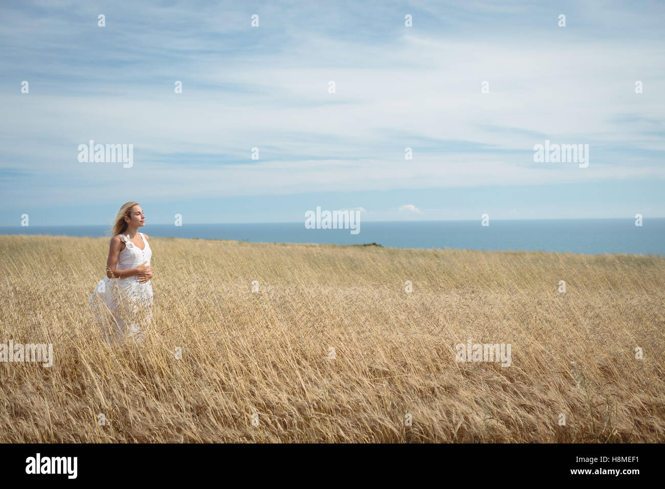 Blonde woman standing in field Stock Photo - Alamy