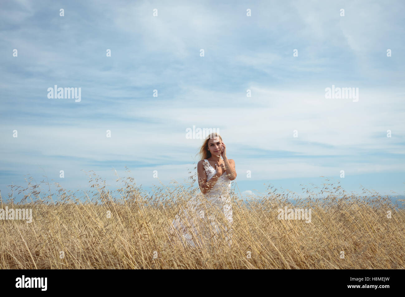 Blonde woman standing in field Stock Photo - Alamy