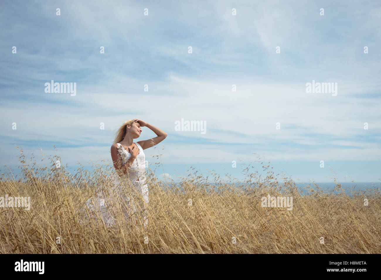 Blonde woman standing in field Stock Photo - Alamy
