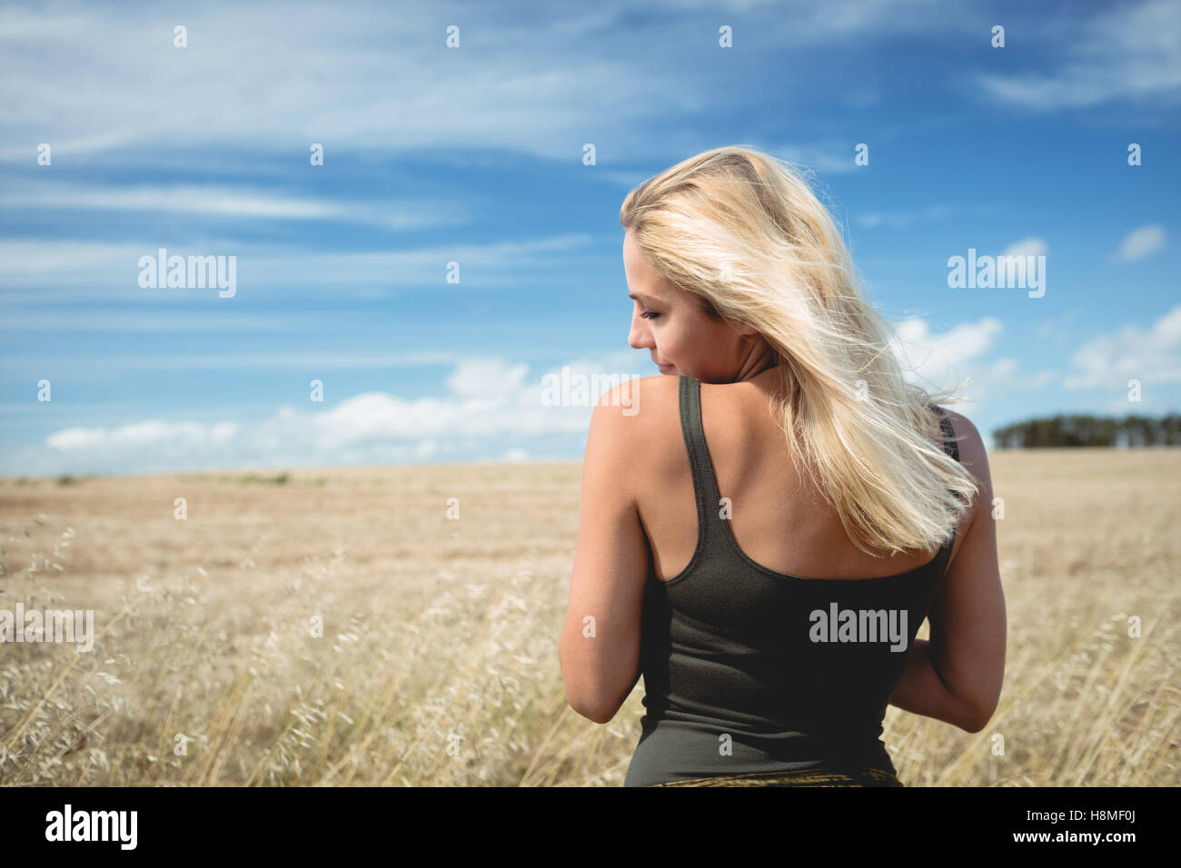 Rear view of blonde woman standing in field Stock Photo - Alamy