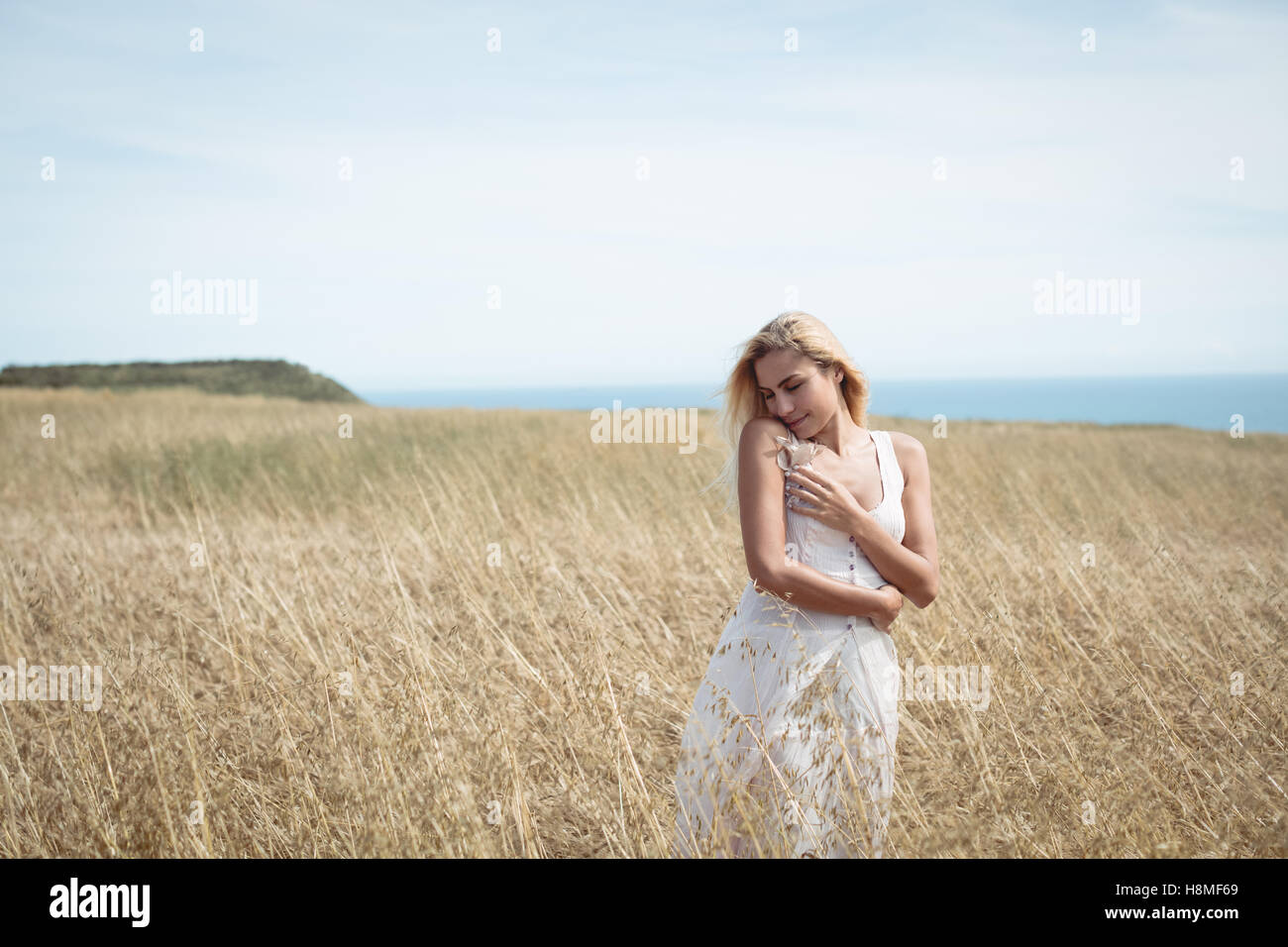 Blonde woman standing in field Stock Photo - Alamy