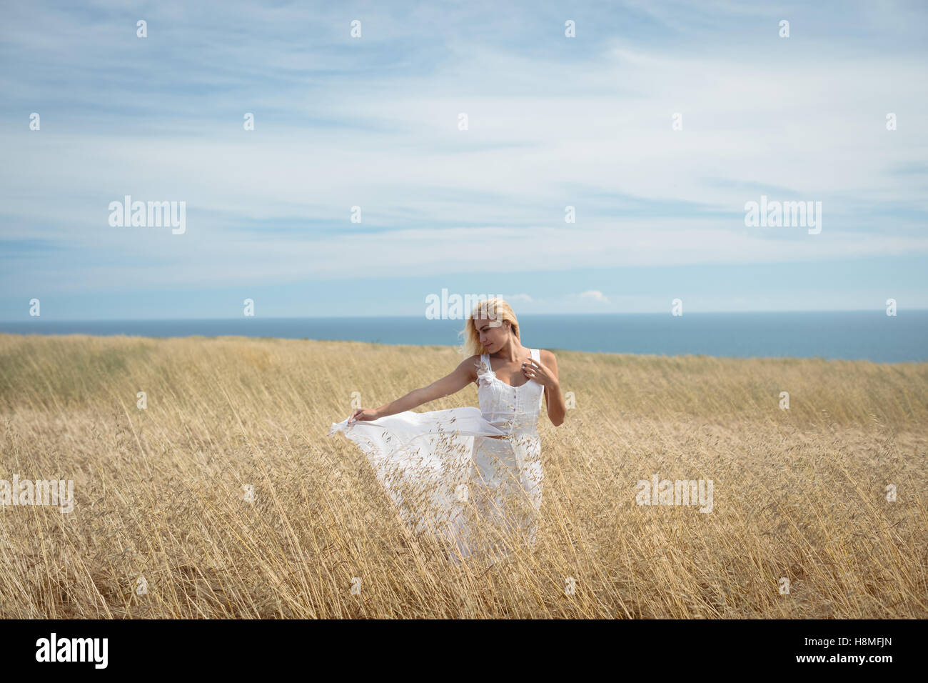 Blonde woman standing in field Stock Photo - Alamy