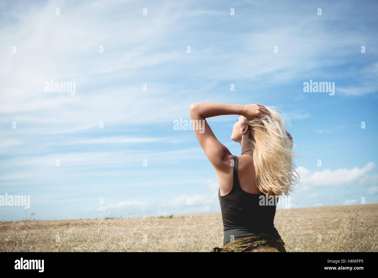 Rear view of blonde woman standing in field Stock Photo - Alamy