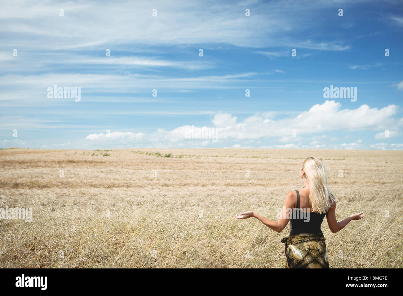 Rear view of blonde woman standing in field Stock Photo - Alamy