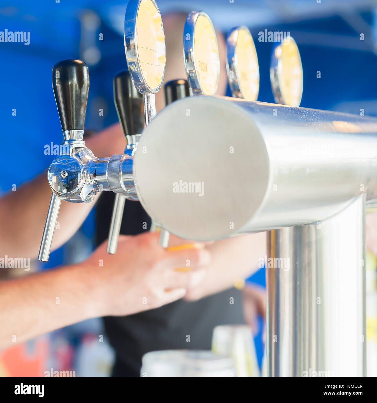 Barman hand at beer tap pouring a drought lager beer serving in a restaurant or pub. Stock Photo