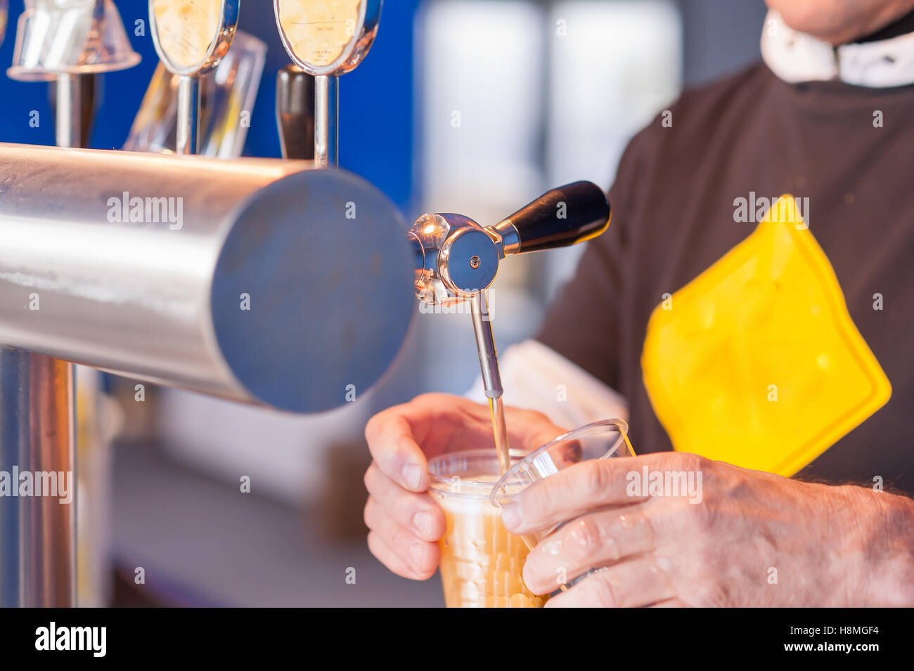 Barman hand at beer tap pouring a draught lager beer serving in a restaurant or pub. Stock Photo