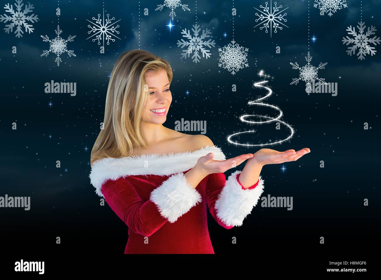 Smiling woman in santa costume pretending to hold a imaginary christmas tree Stock Photo