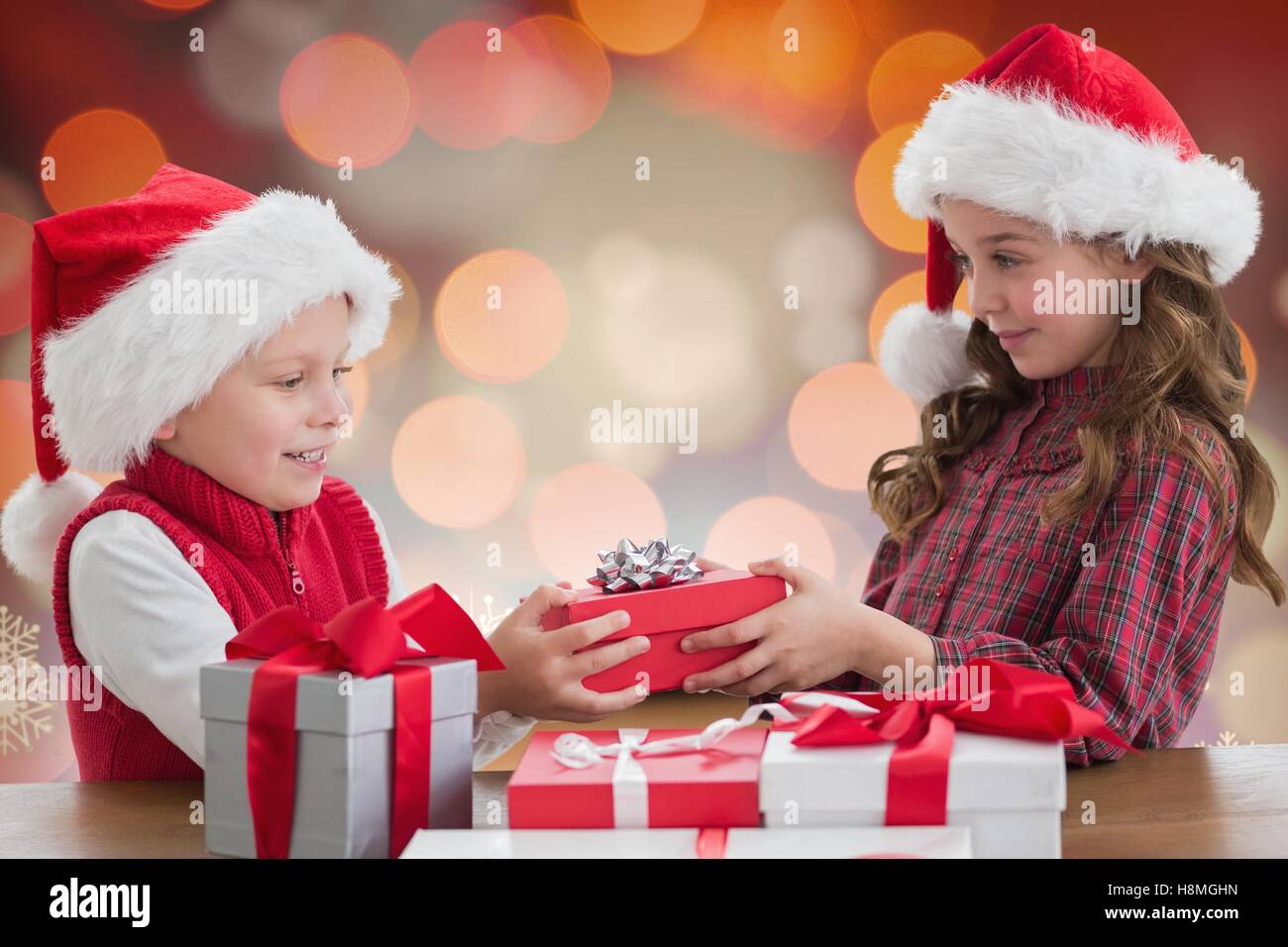Two kids in santa hat sharing christmas gift boxes Stock Photo