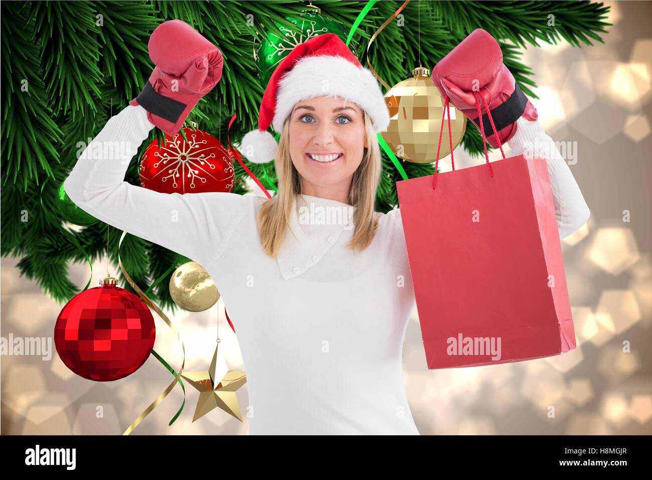 Beautiful woman in santa hat and boxing gloves holding shopping bag Stock Photo