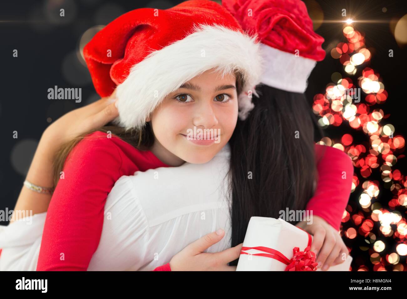 Mother and daughter in santa hat embracing each other Stock Photo