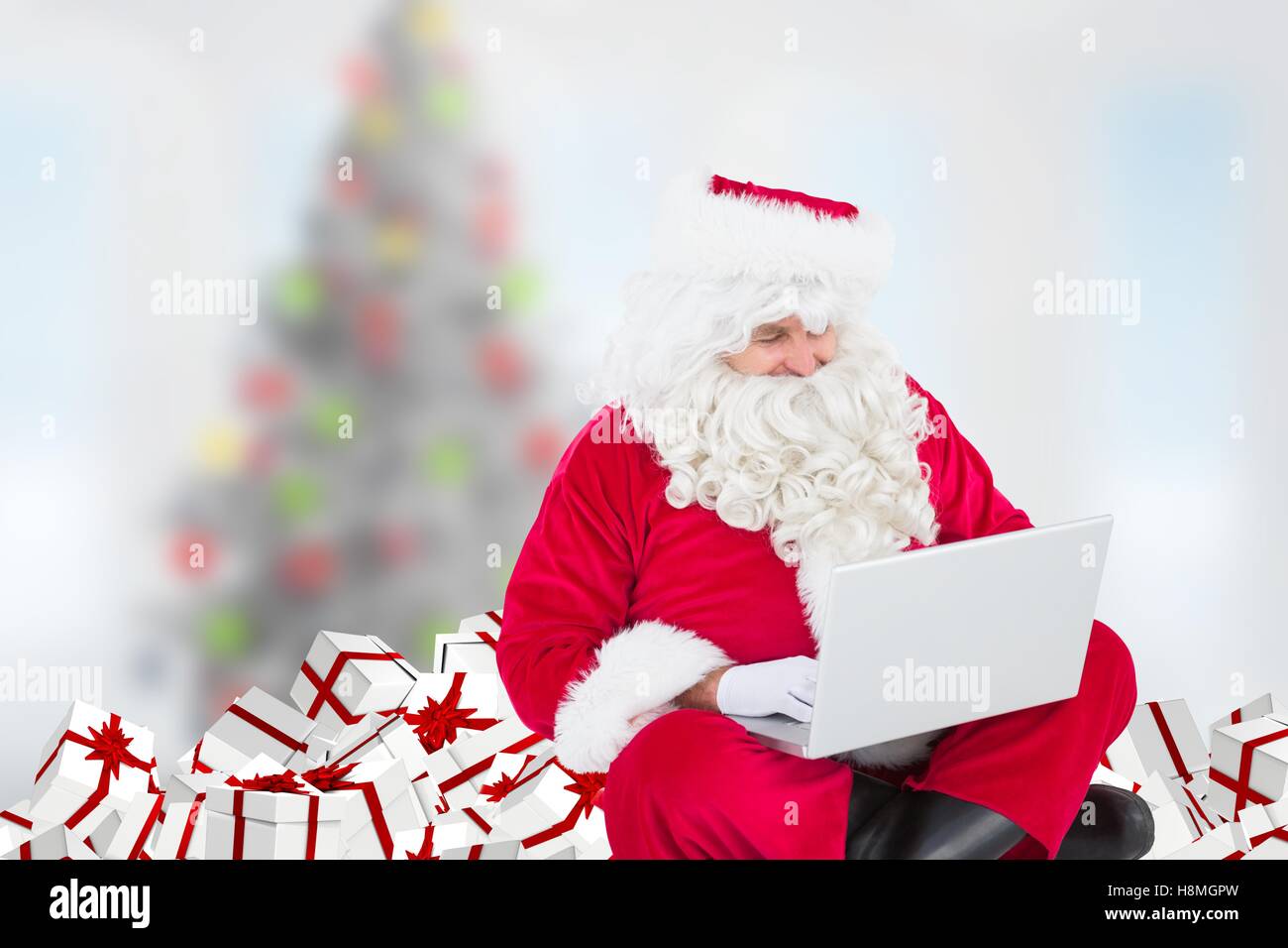 Santa claus sitting with gifts and using laptop Stock Photo