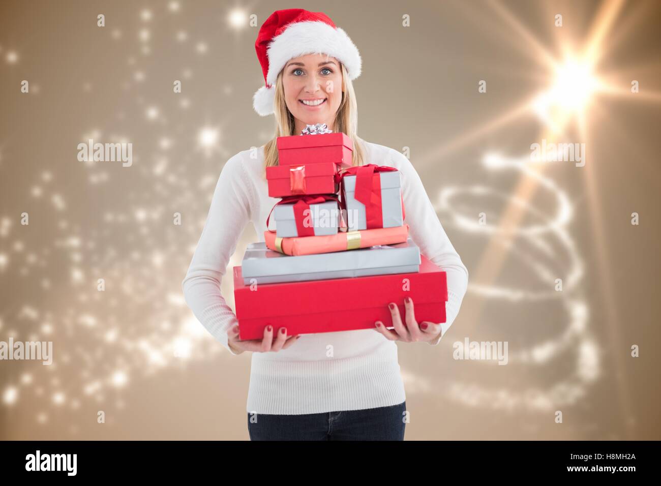 Smiling woman in santa hat holding stack of christmas gifts Stock Photo