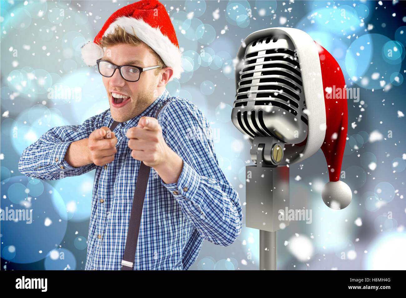 Man gesturing towards microphone with santa hat against digitally generated background Stock Photo