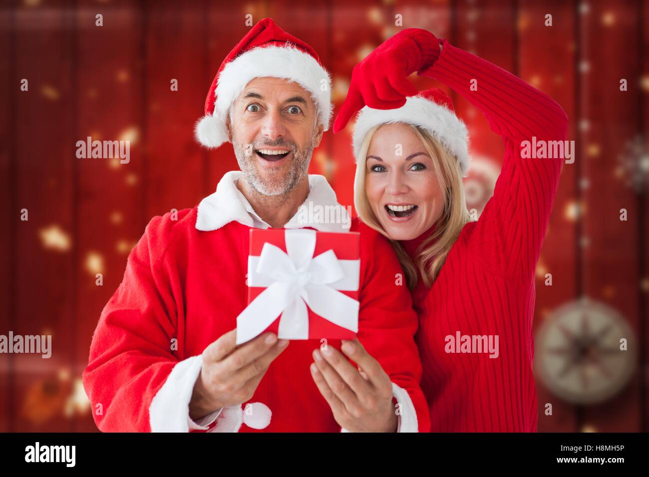 Portrait of happy couple in santa costume holding christmas gift Stock Photo
