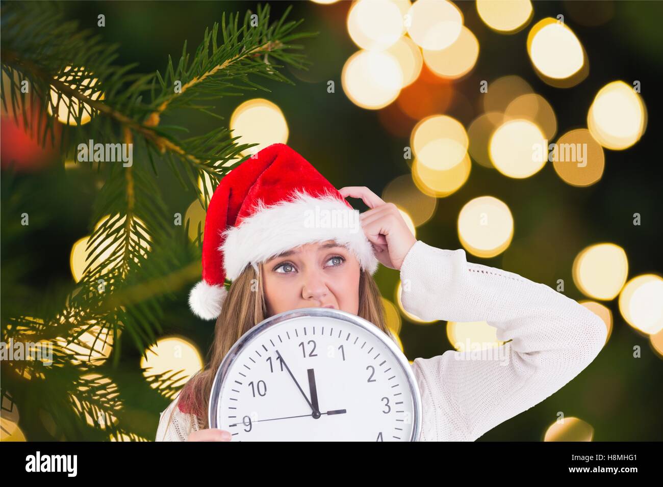 Thoughtful woman in santa hat holding a clock Stock Photo - Alamy