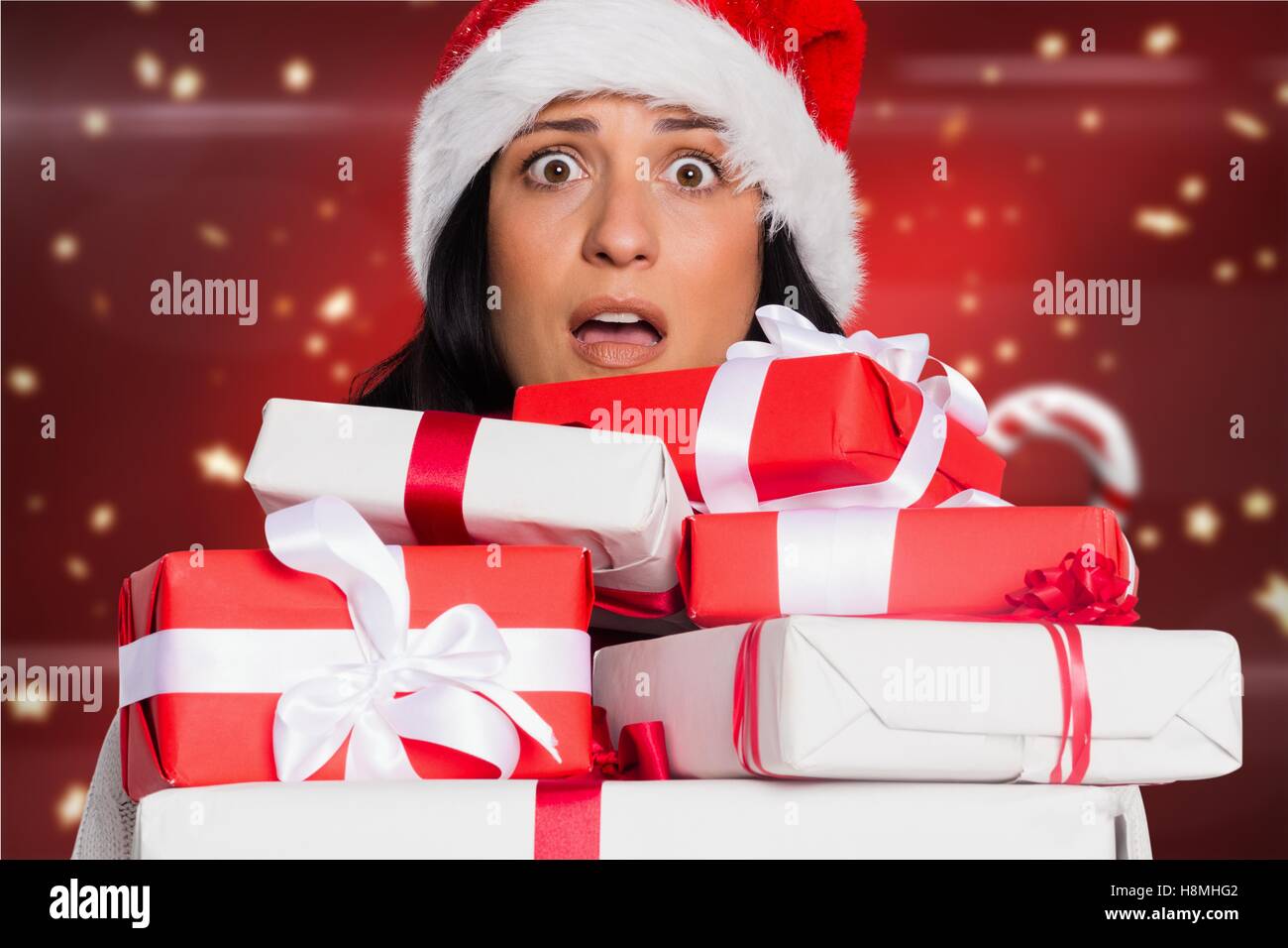 Shocked woman in santa hat holding stack of gift boxes Stock Photo