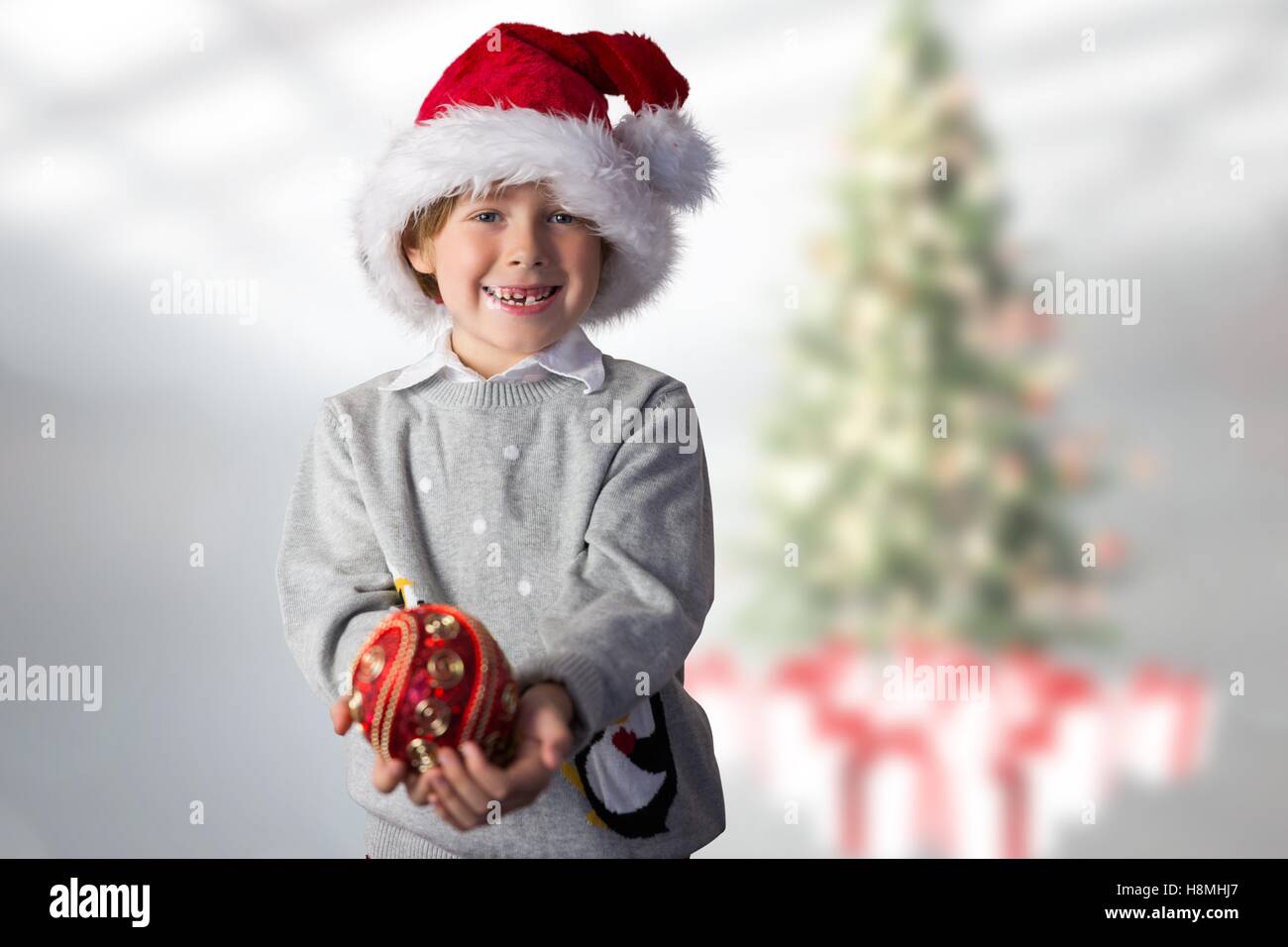 Boy in santa hat holding christmas bauble Stock Photo
