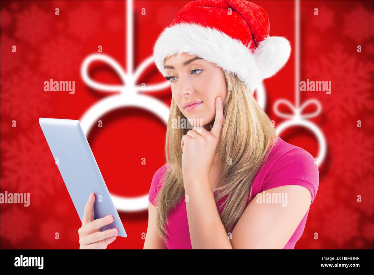 Thoughtful beautiful woman in santa hat using digital tablet Stock Photo