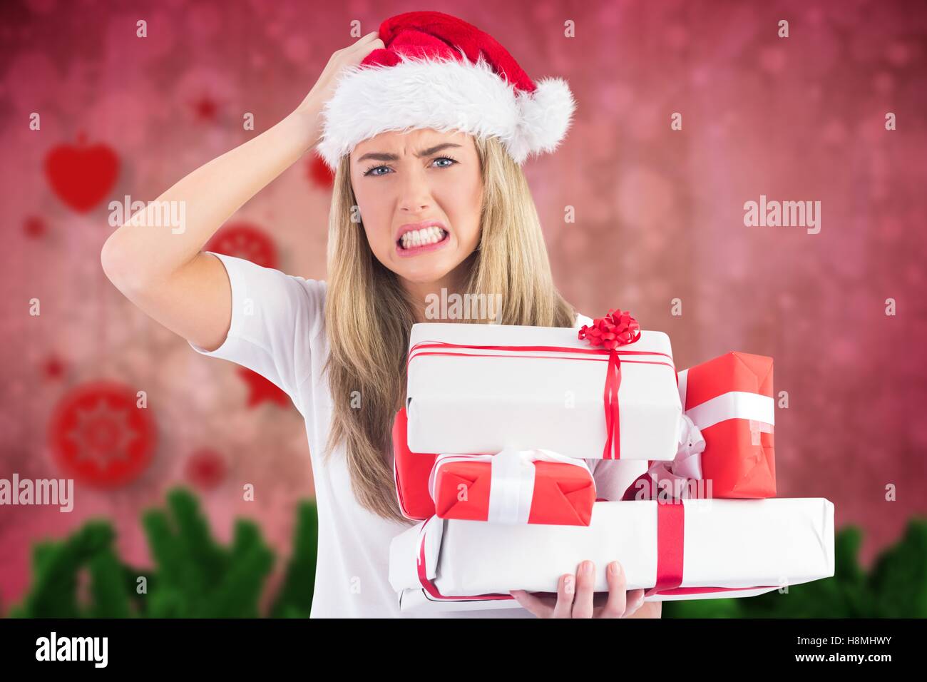 Frustrated woman in santa hat holding stack of gifts Stock Photo