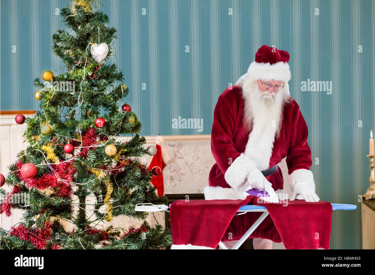 Santa claus ironing his clothes Stock Photo