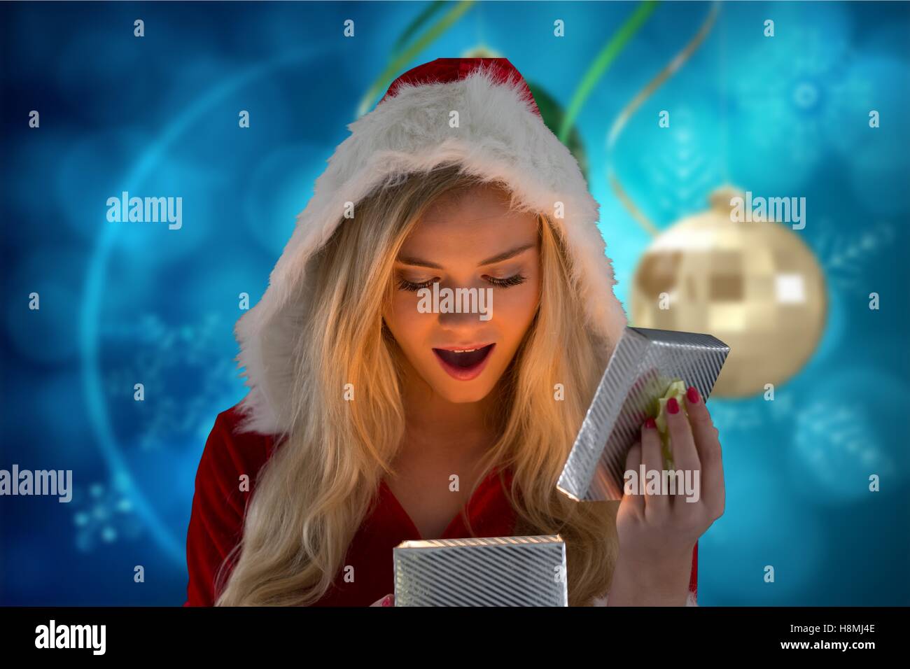 Surprised woman in santa hat looking at christmas gifts Stock Photo