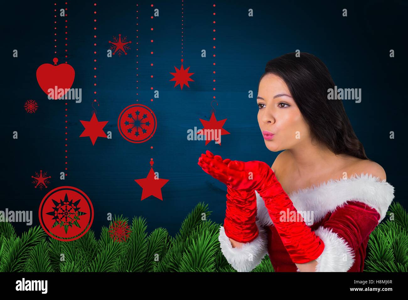 Woman in santa costume blowing a kiss against christmas background Stock Photo