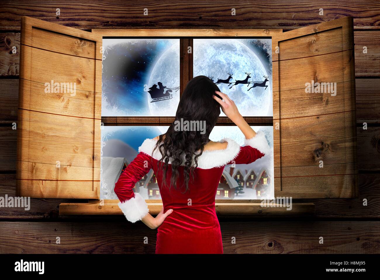 Woman in santa costume looking through window Stock Photo