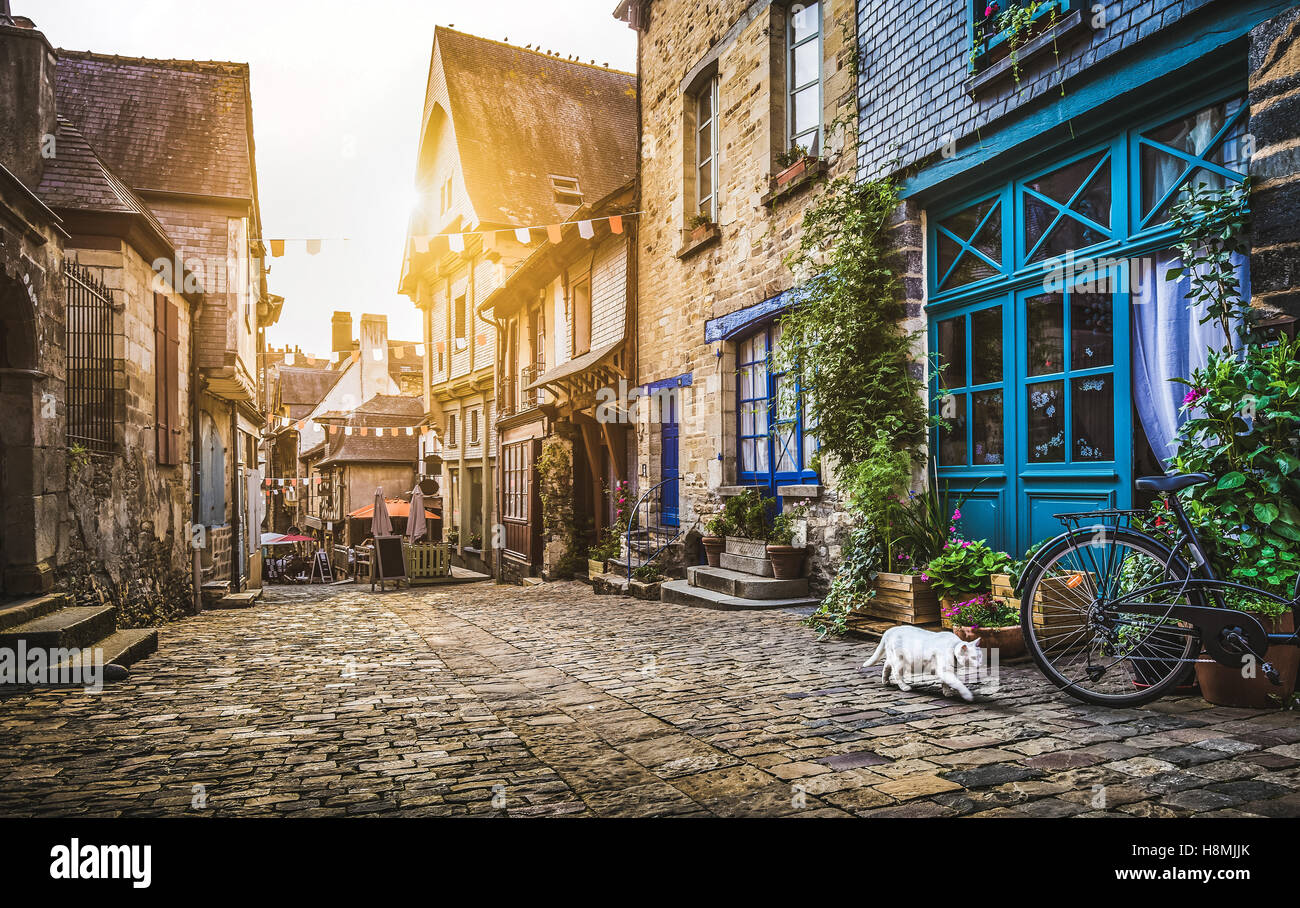 Charming street scene in an old medieval town in Europe at sunset with retro vintage style pastel toned filter and lens flare sunshine effect Stock Photo