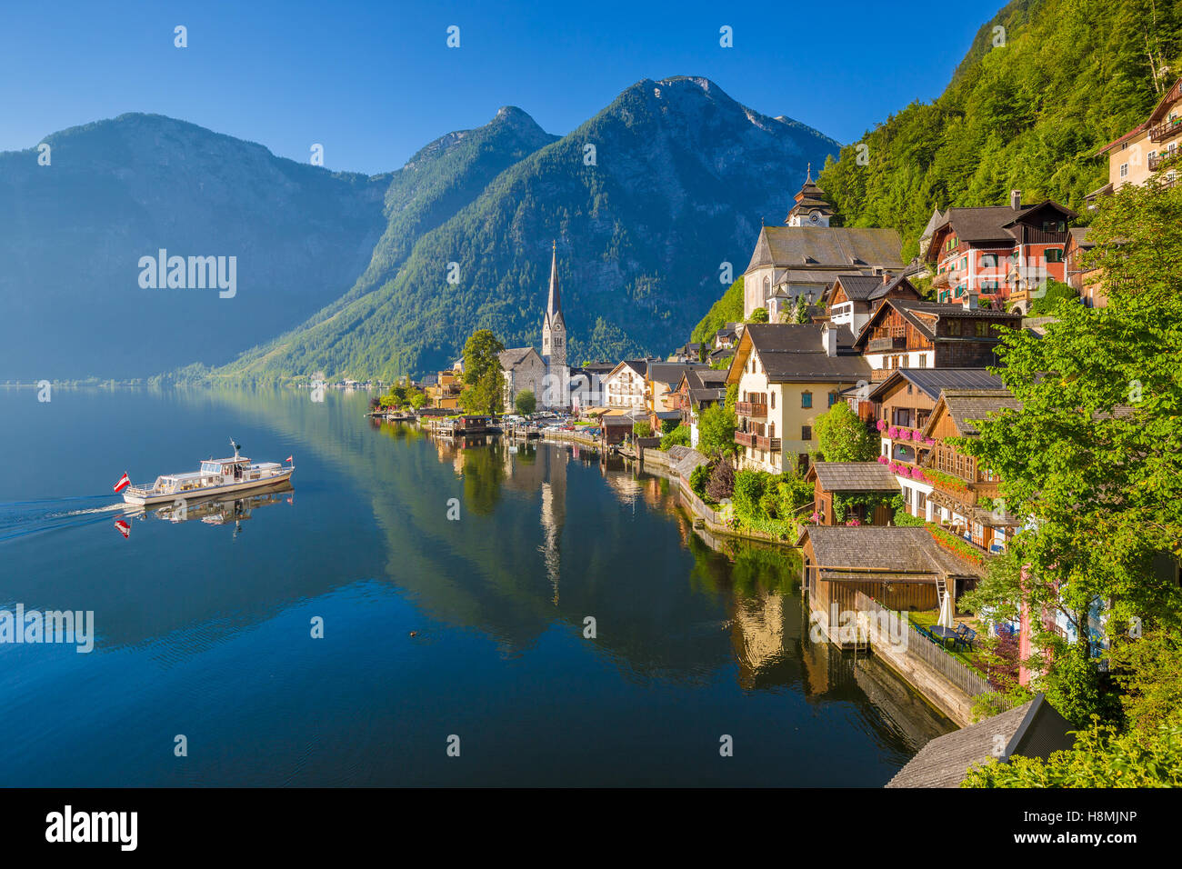Classic postcard view of famous Hallstatt lakeside town in the Alps with ship in beautiful morning light, Salzkammergut, Austria Stock Photo