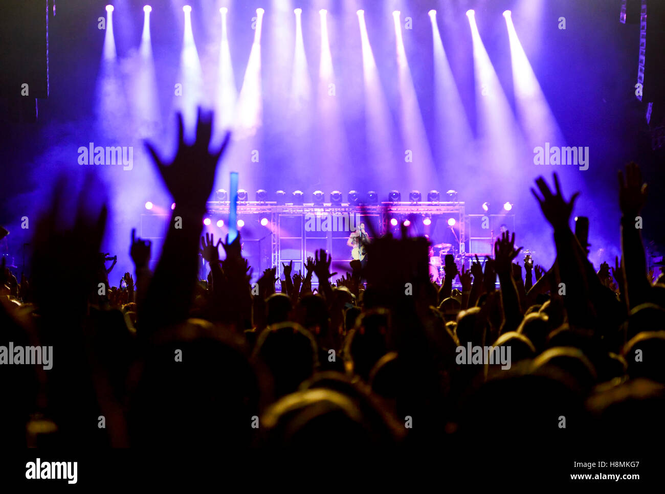 Concert stage with silhouetted hands raised Stock Photo