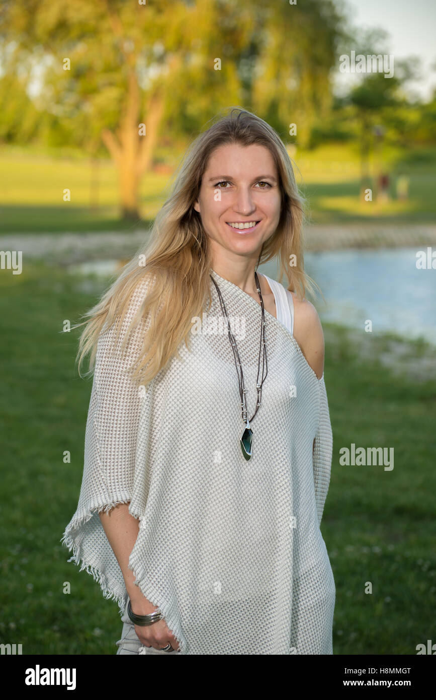 Attractive blonde young woman in a park with blurred background Stock Photo