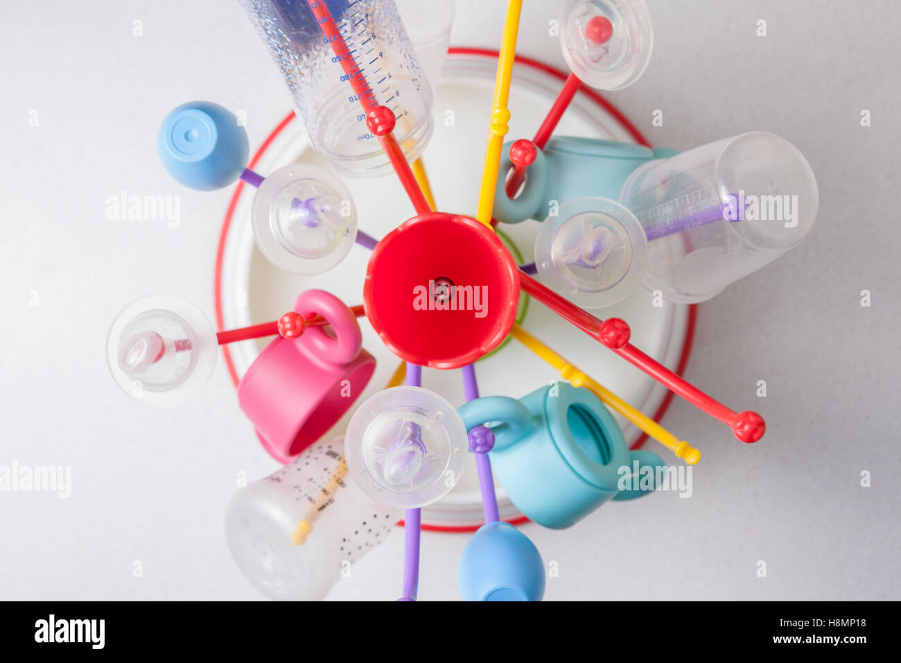 Baby drainer full of plastic tableware objects as baby bottles. High view angle Stock Photo