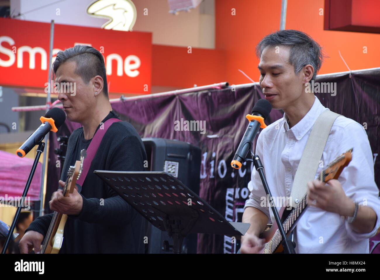 Hong Kong, China - Asian guitarist and bassist playing music and singing on the street Stock Photo