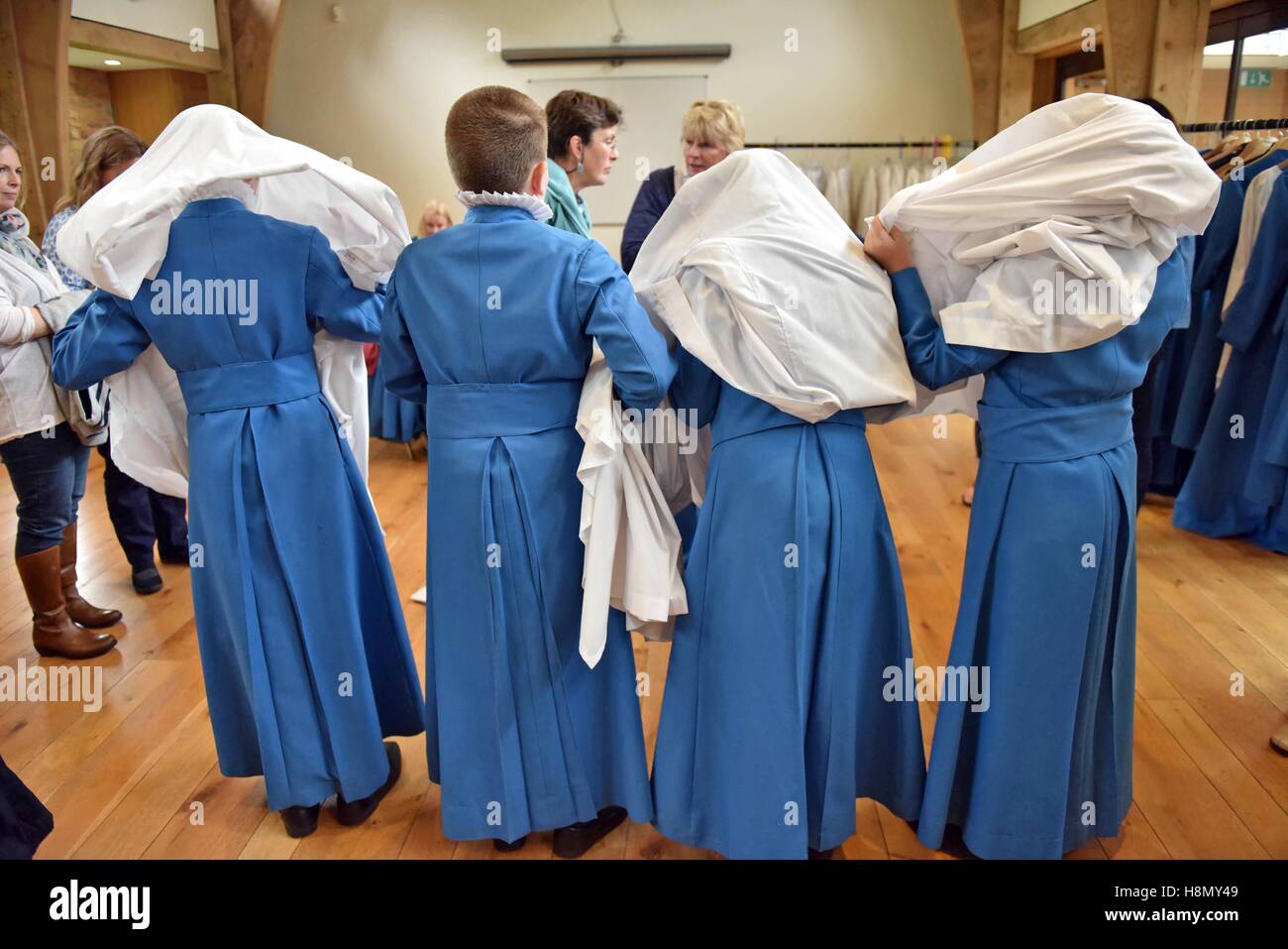 Choristers at cassock fitting before first evensong of the year trying on surplices over head