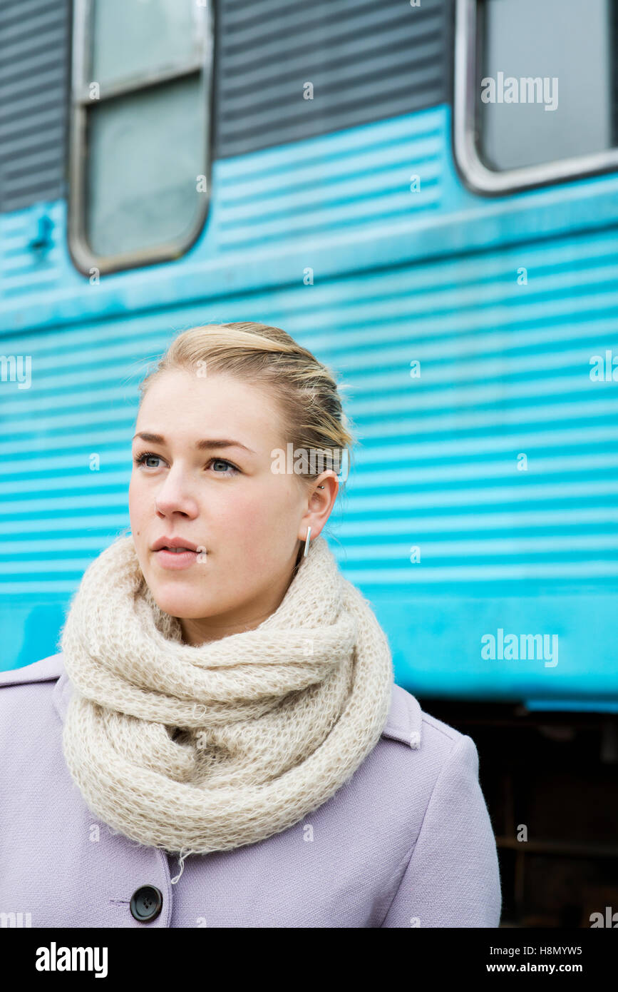 Young woman wearing overcoat with train in background Stock Photo