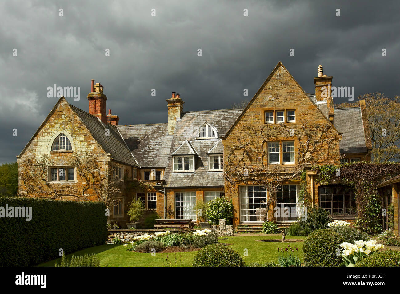 Coton Manor with a dramatic black cloudy sky, near Guilsborough, Northamptonshire, England, UK. Stock Photo