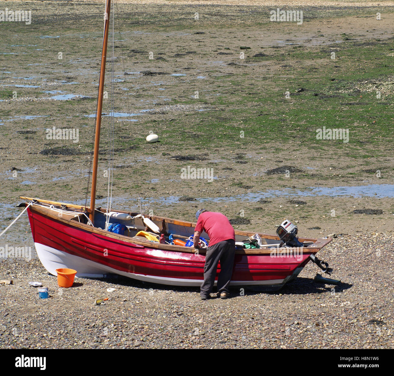 Man working on maintaining red fishing boat at Weston Shore, Woolston, Southampton, Hampshire UK Stock Photo