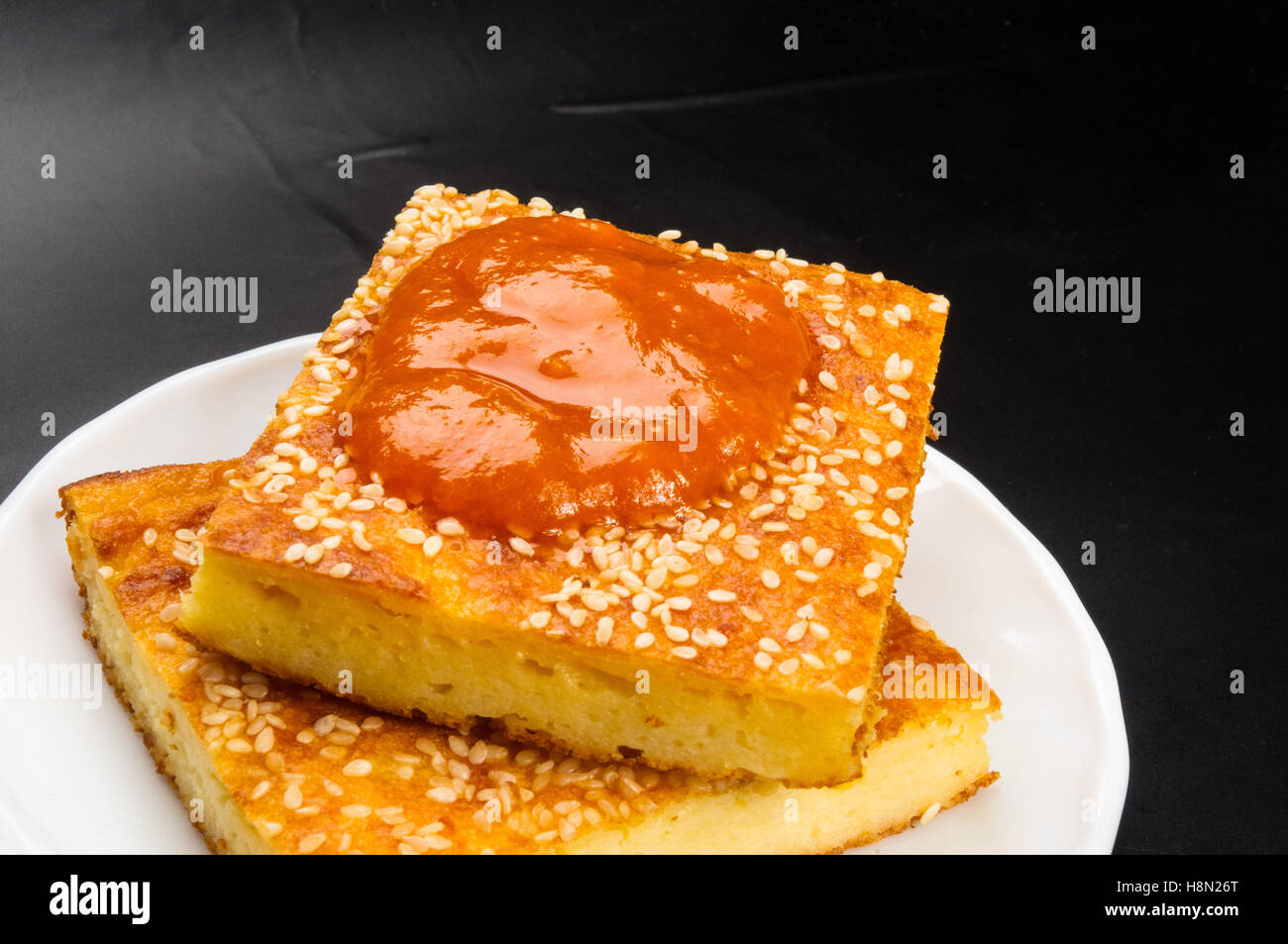 Slice of cheesecake with sesame seeds and apricot jam on a black background Stock Photo Alamy