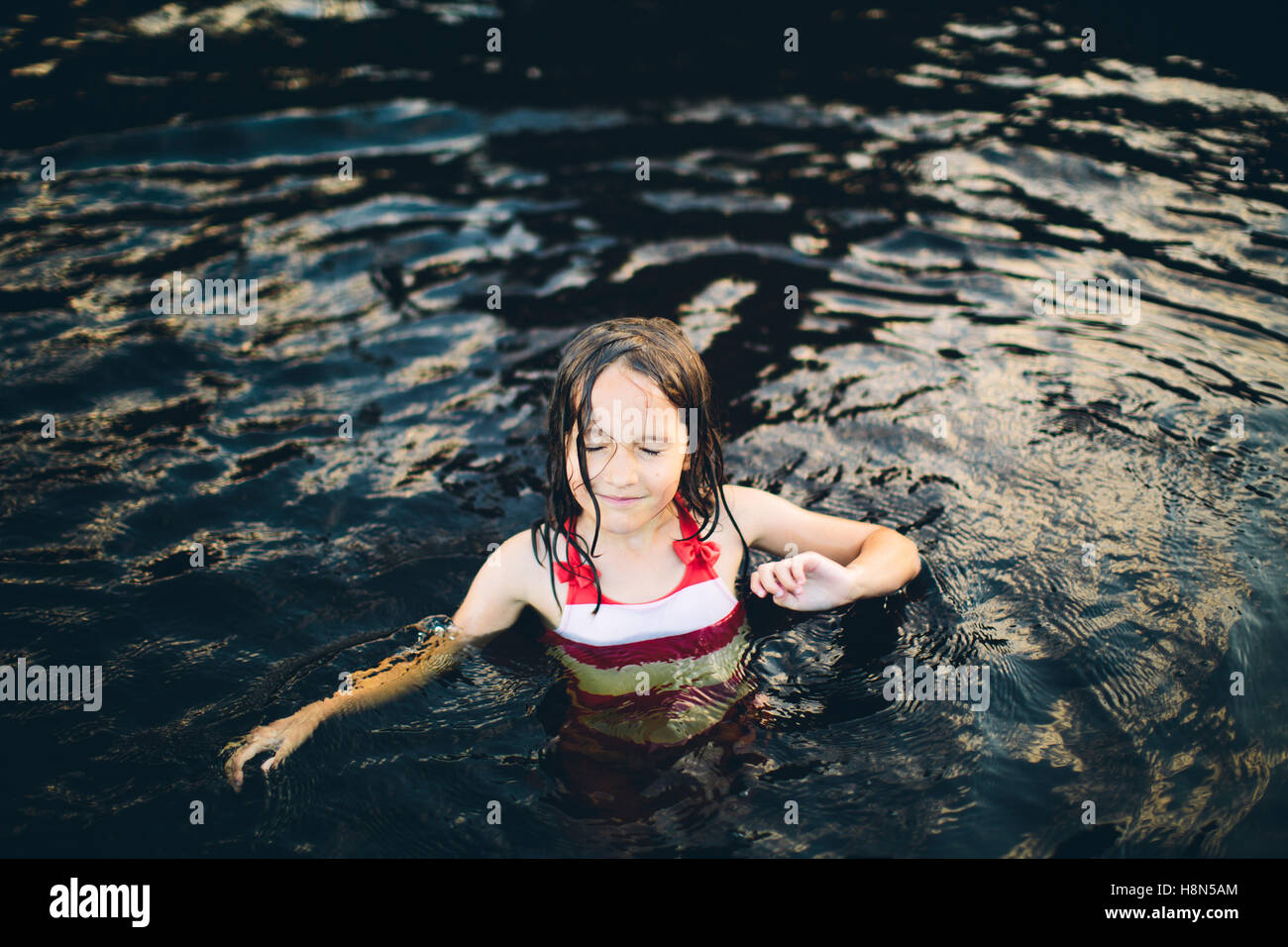 Girl (8-9) in swimming costume standing in water Stock Photo