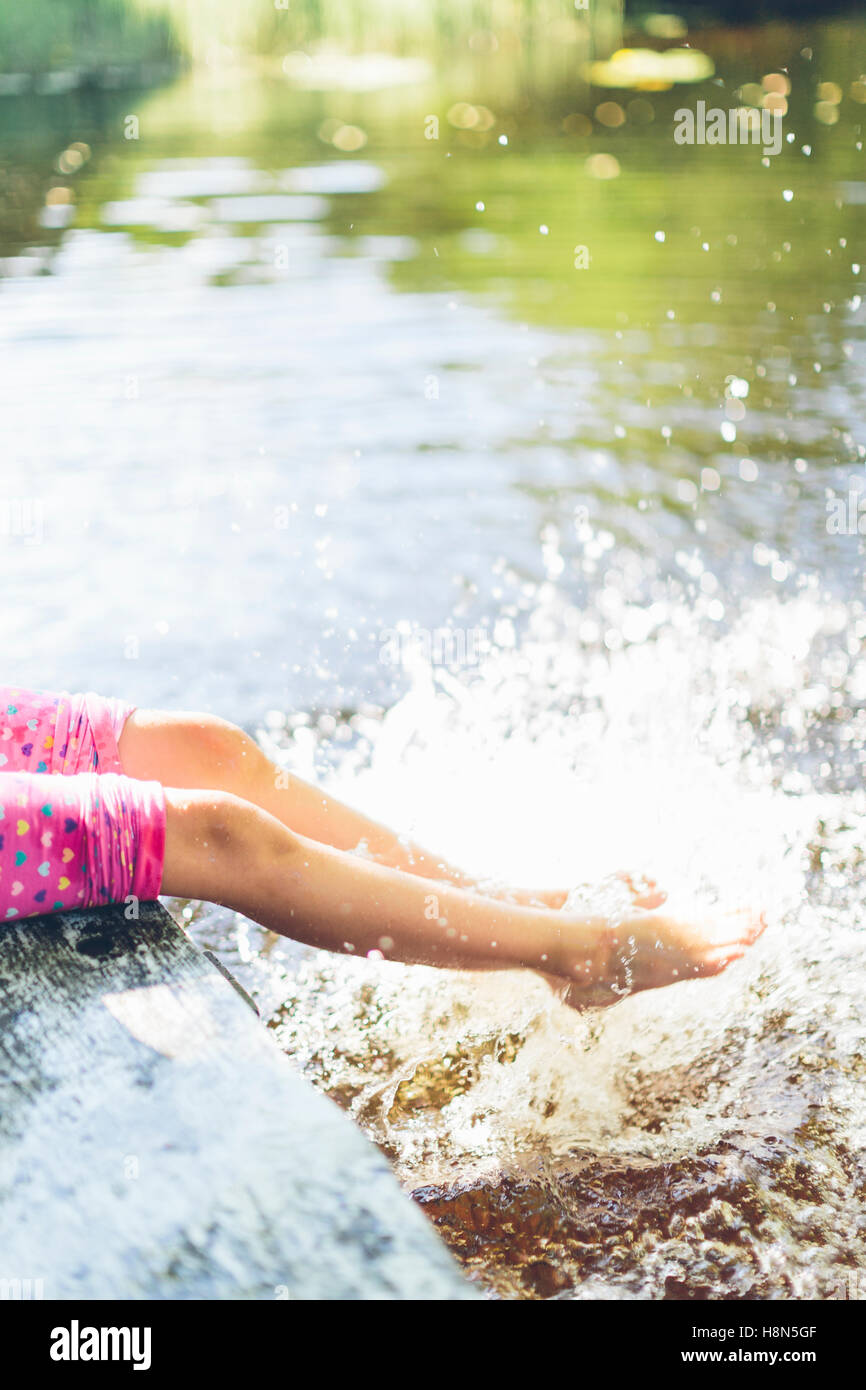 Low section of girl (8-9) splashing water with legs Stock Photo