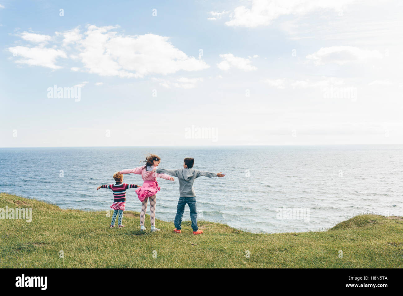 Two girls (4-5, 10-11) and boy (9-10) looking at sea Stock Photo