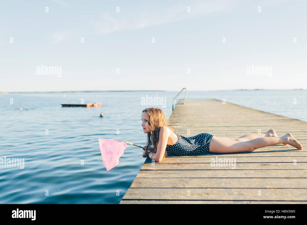 Girl (10-11) lying on pier and fishing Stock Photo