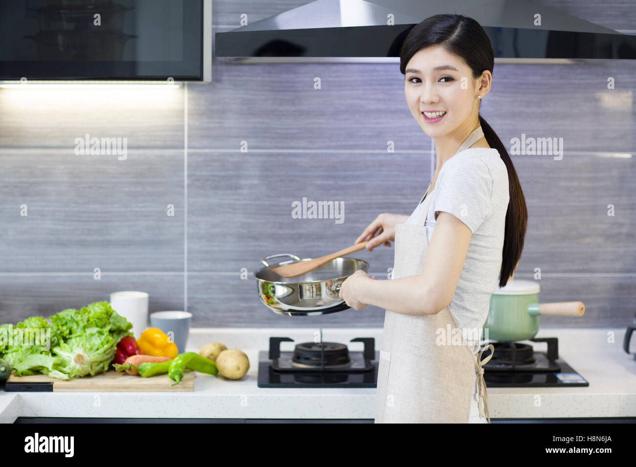 Happy young Chinese woman cooking in kitchen Stock Photo Alamy