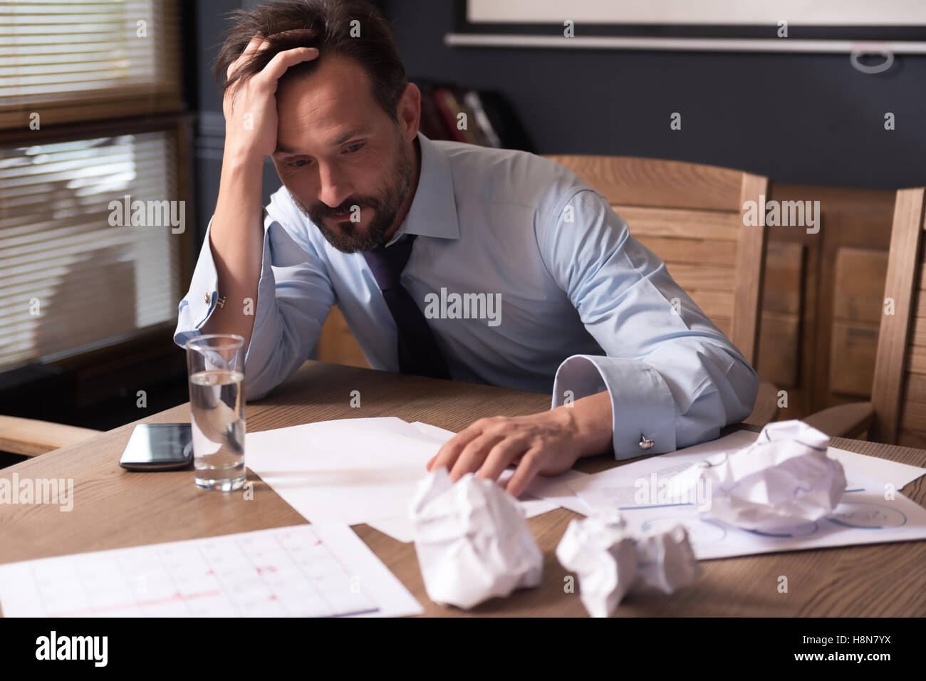 Exhausted cheerless man working long hours Stock Photo