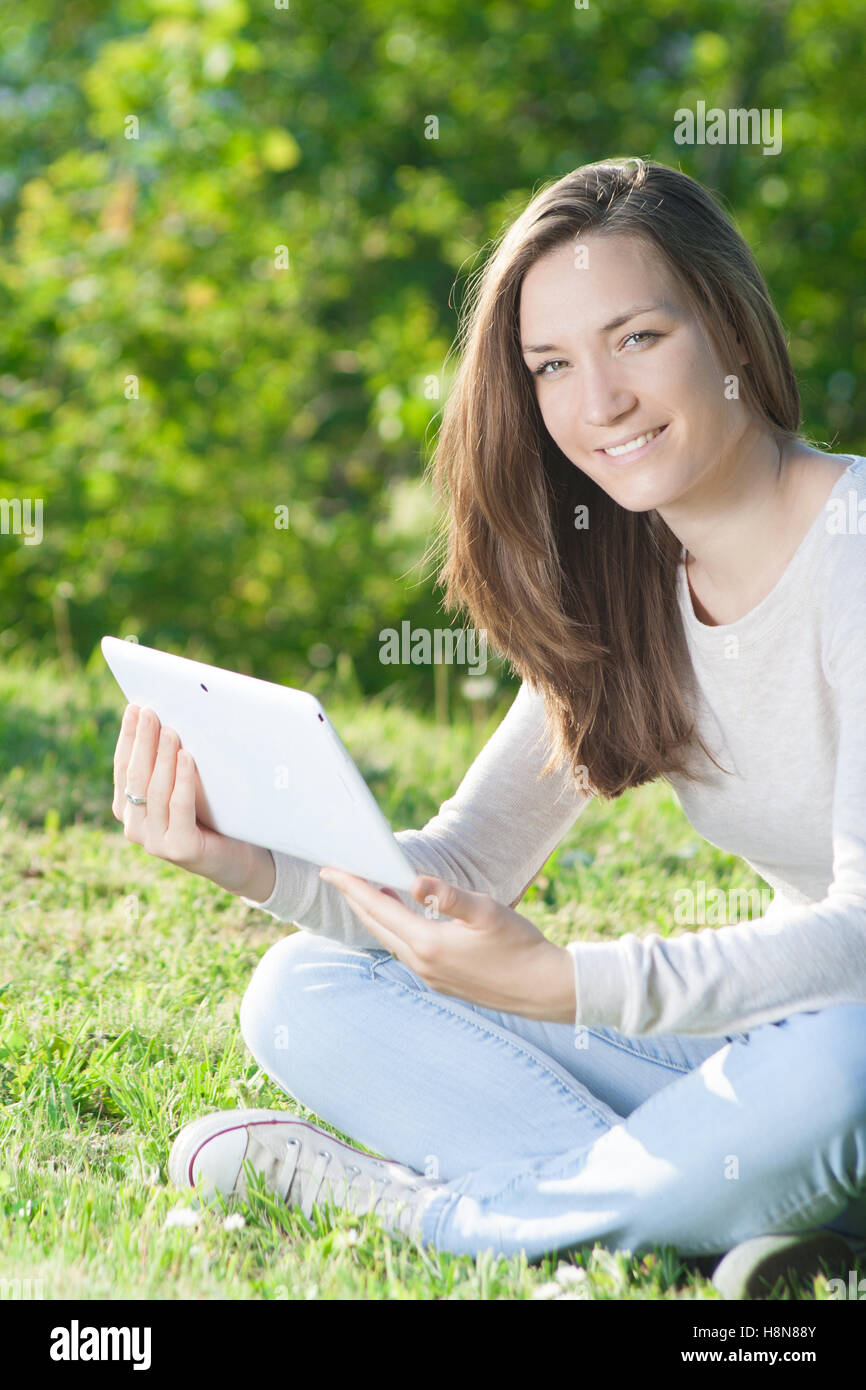 Young woman using tablet computer outdoors in  park Stock Photo