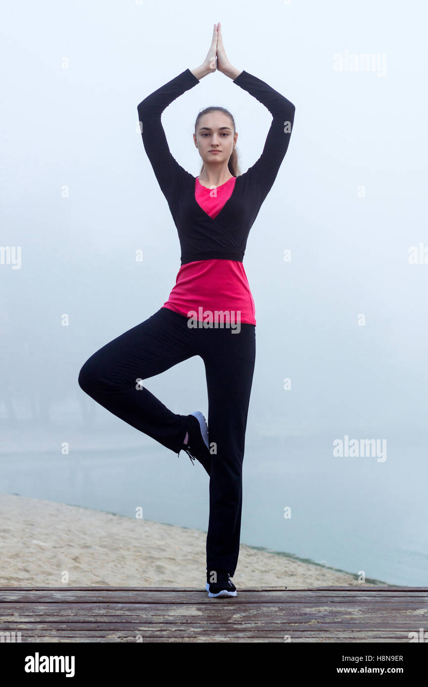 Young pretty slim fitness sporty woman does yoga exercises during training workout outdoor Stock Photo