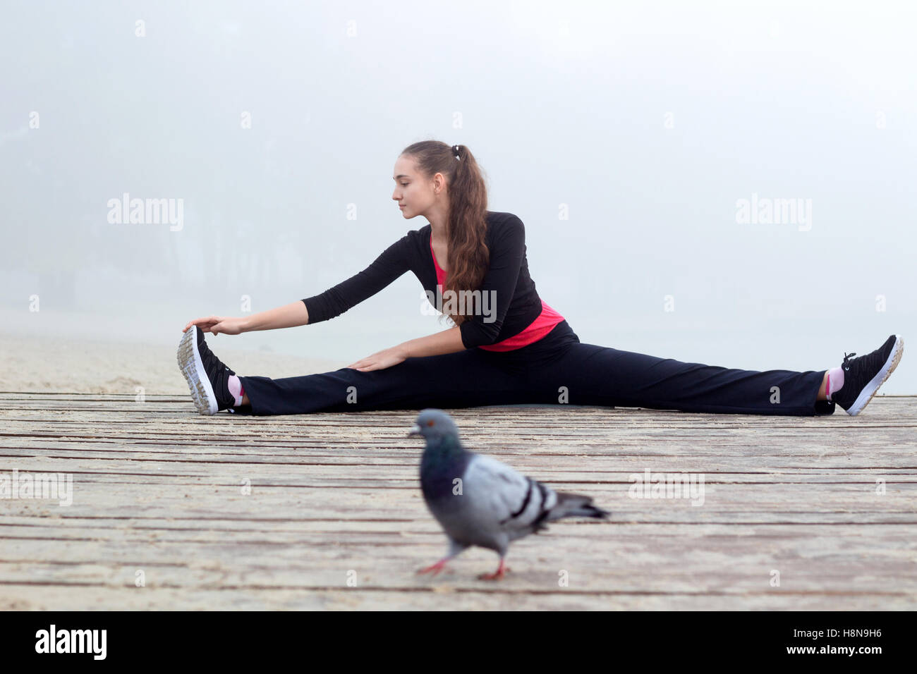 Young pretty slim fitness sporty woman does stretching exercises during training workout outdoor Stock Photo