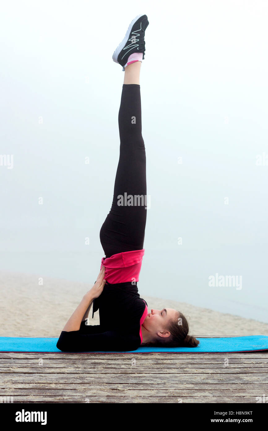 Young pretty slim fitness sporty woman does yoga exercises during training workout outdoor Stock Photo